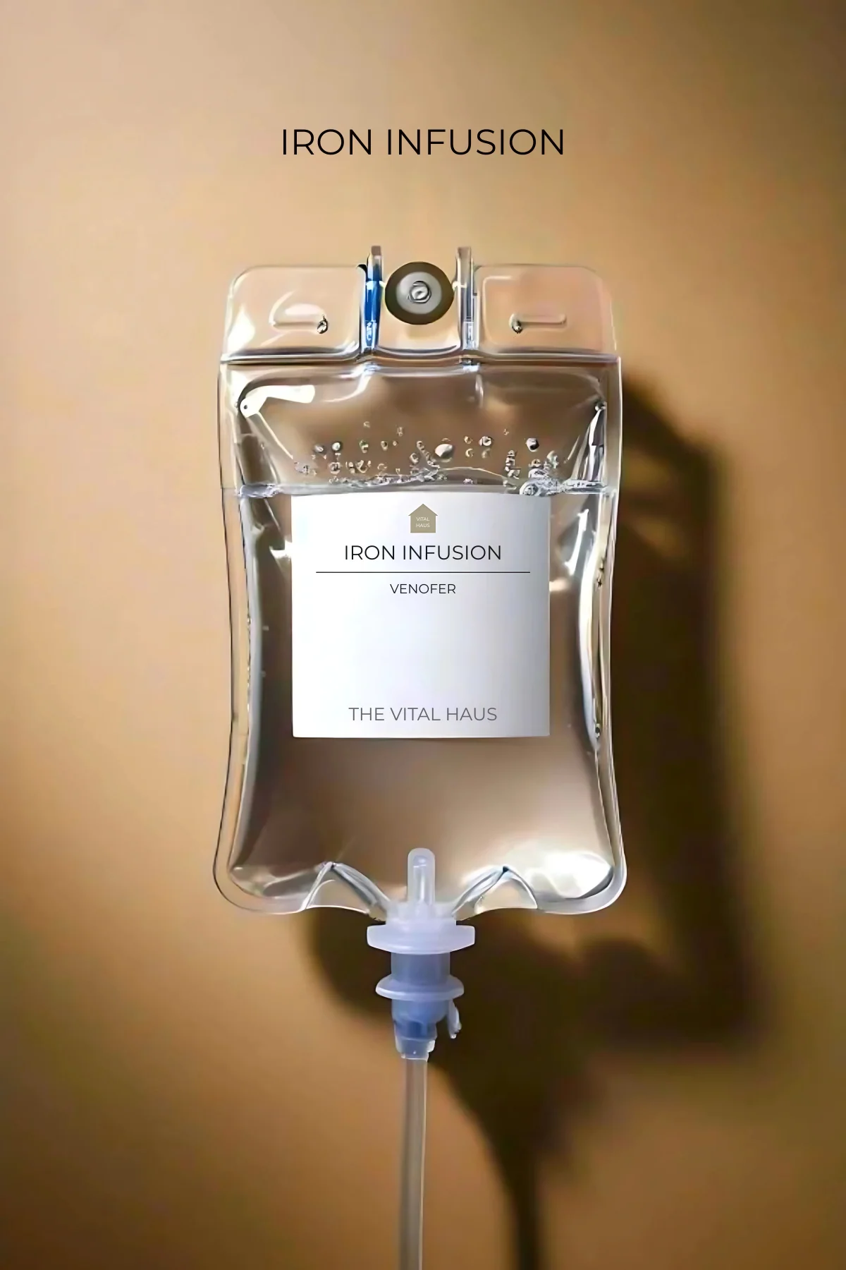 The image shows a clear plastic IV drip bag labeled with 'Iron Infusion' containing a solution, attached to a transparent tube connected to a medical device, placed on a beige background with a watermark in the lower right corner that reads 'IRON INFUSION'.