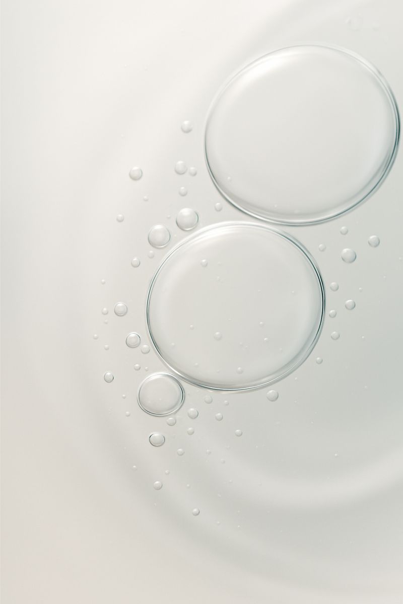 The image shows a close-up of two soap bubbles with droplets around them on a white background.